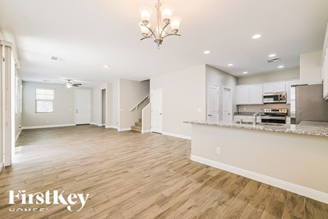 A spacious living room with wooden flooring and a chandelier.