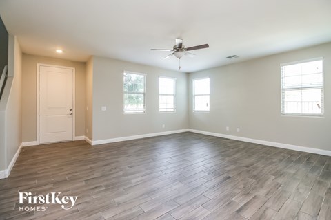 the spacious living room with wood floors and a ceiling fan