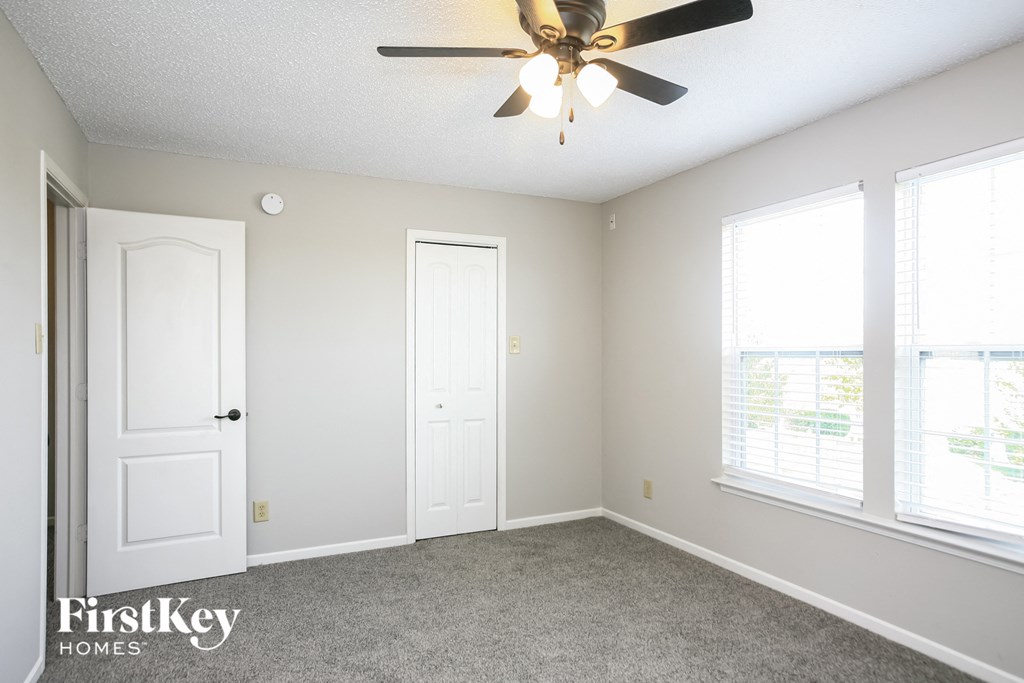 a bedroom with a ceiling fan and two windows