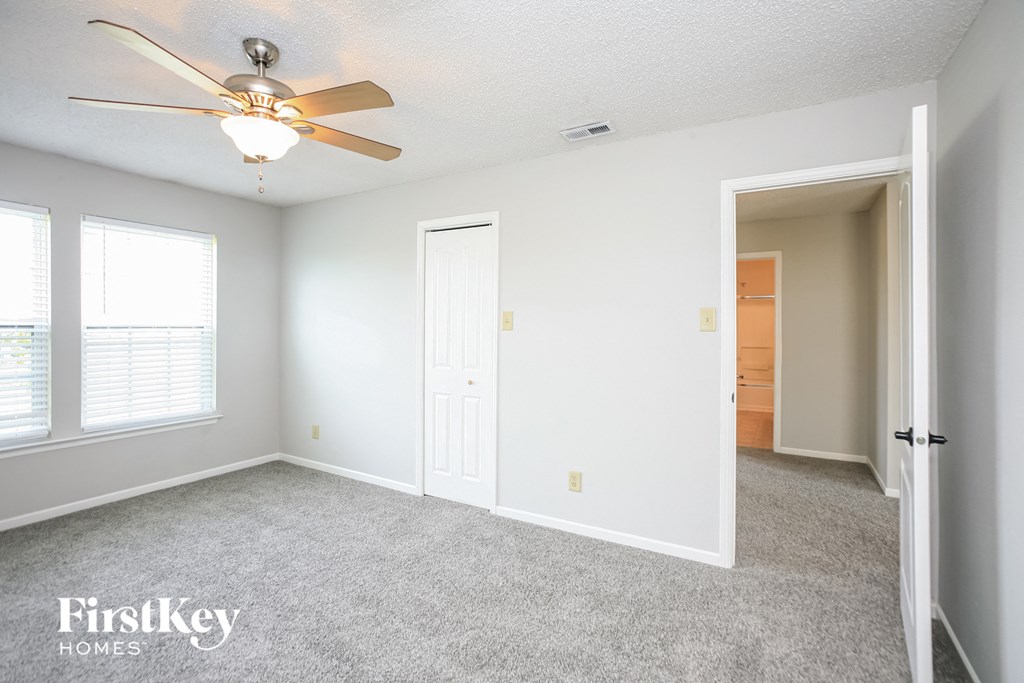 a bedroom with a ceiling fan and a door to a closet