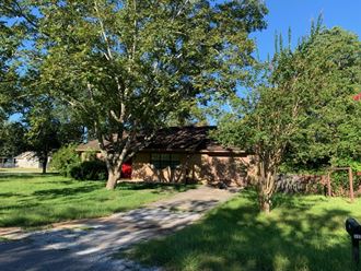 a house with a driveway and trees in front of it