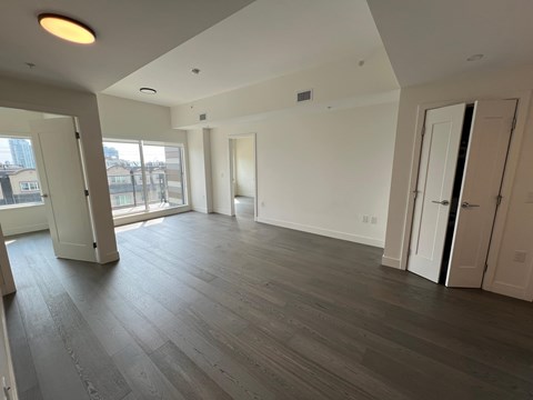 A spacious room with wooden flooring and white walls.