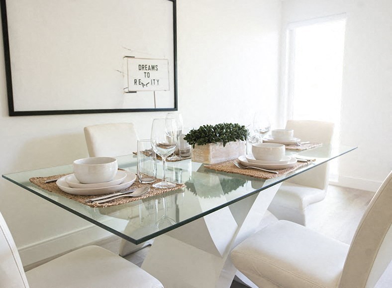 a white dining room with a glass table and white chairs