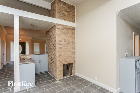 A room with a brick fireplace and a kitchen area.