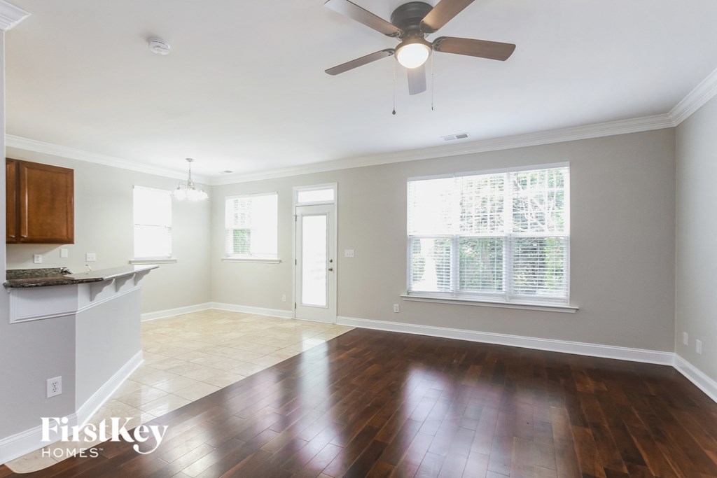 A spacious room with a ceiling fan and hardwood floors.