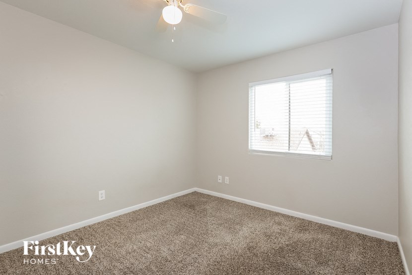 a bedroom with carpet and a window and a ceiling fan