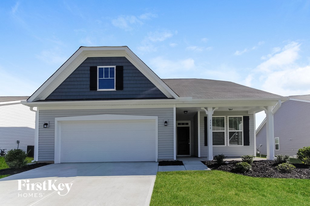 a white house with a garage door and a lawn