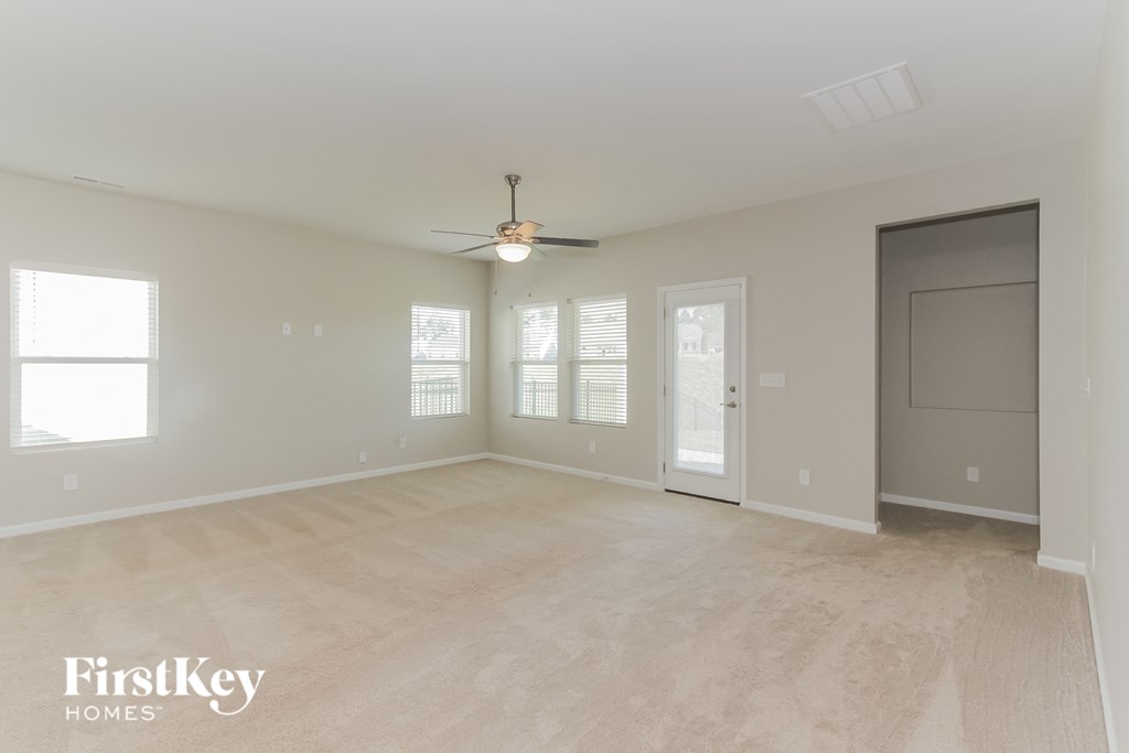 an empty living room with a ceiling fan and windows