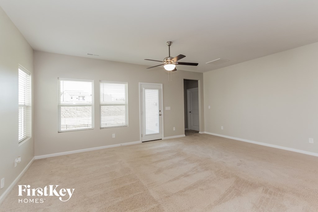 an empty living room with a ceiling fan and window