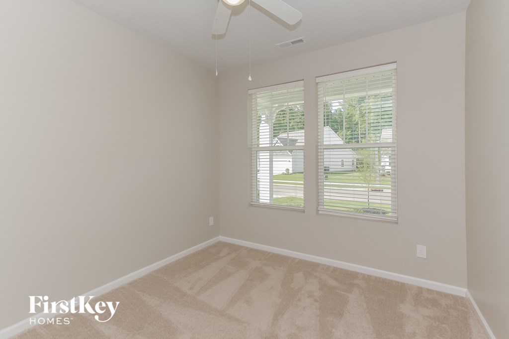 the living room of an empty house with two windows and a ceiling fan