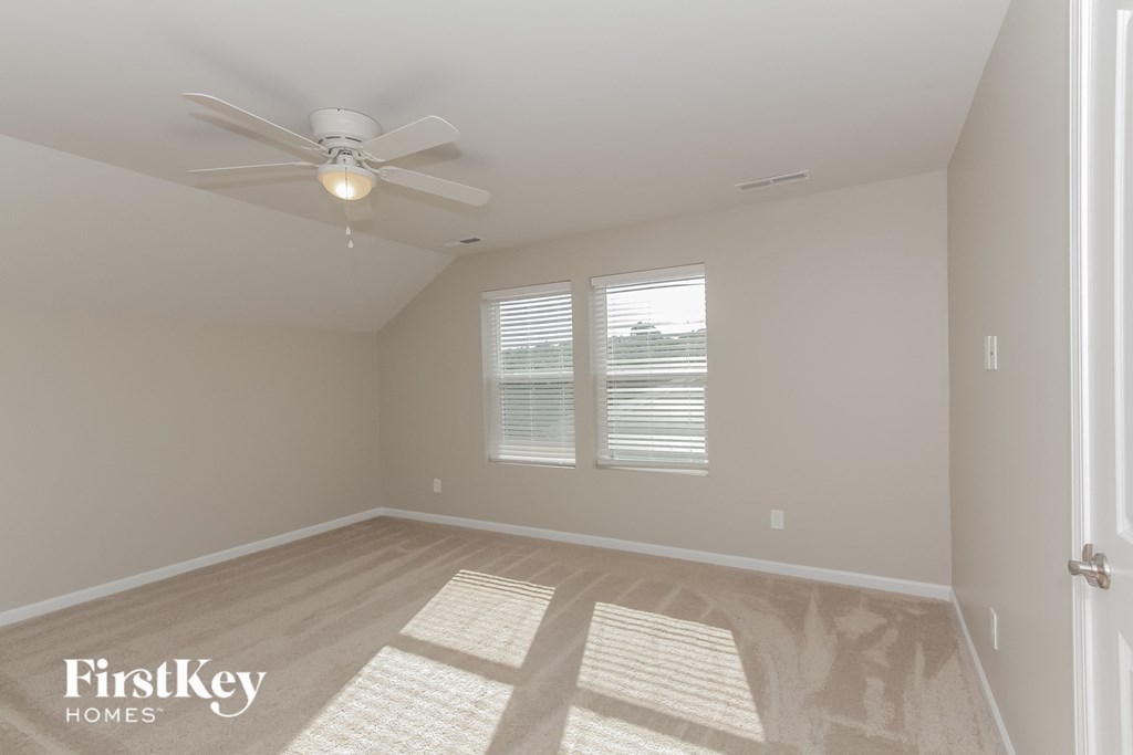 an empty room with a ceiling fan and two windows