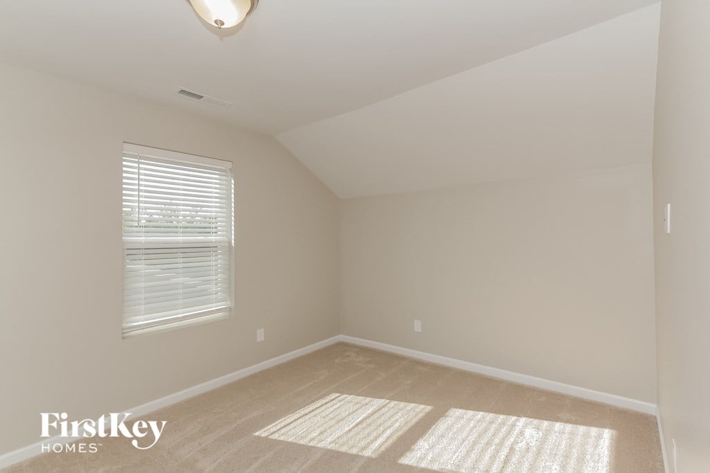 a bedroom with a large window and beige carpet and a white ceiling and window