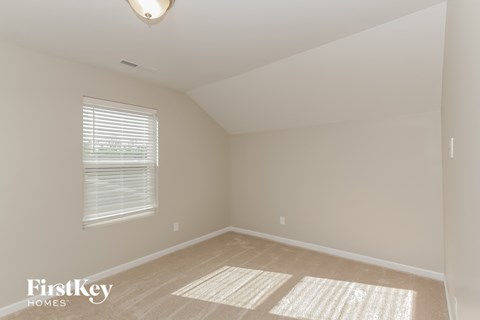 a bedroom with a large window and beige carpet and a white ceiling and window