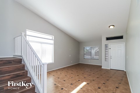 an empty living room with a staircase and a white door