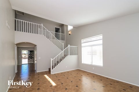 an empty living room with a staircase and a window