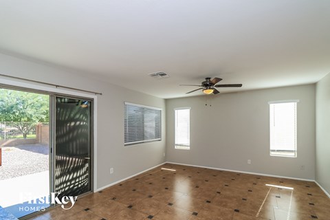 an empty living room with a ceiling fan and a sliding glass door
