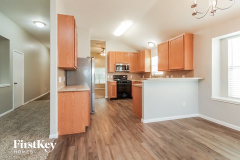 an open kitchen and living room with wood flooring and wooden cabinets
