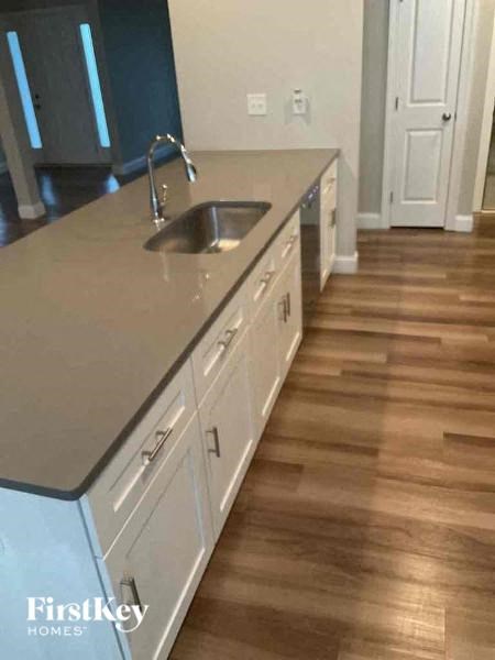 A kitchen with a sink and wooden floors.