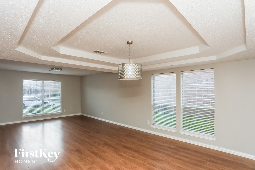 A room with wooden floors and a chandelier hanging from the ceiling.