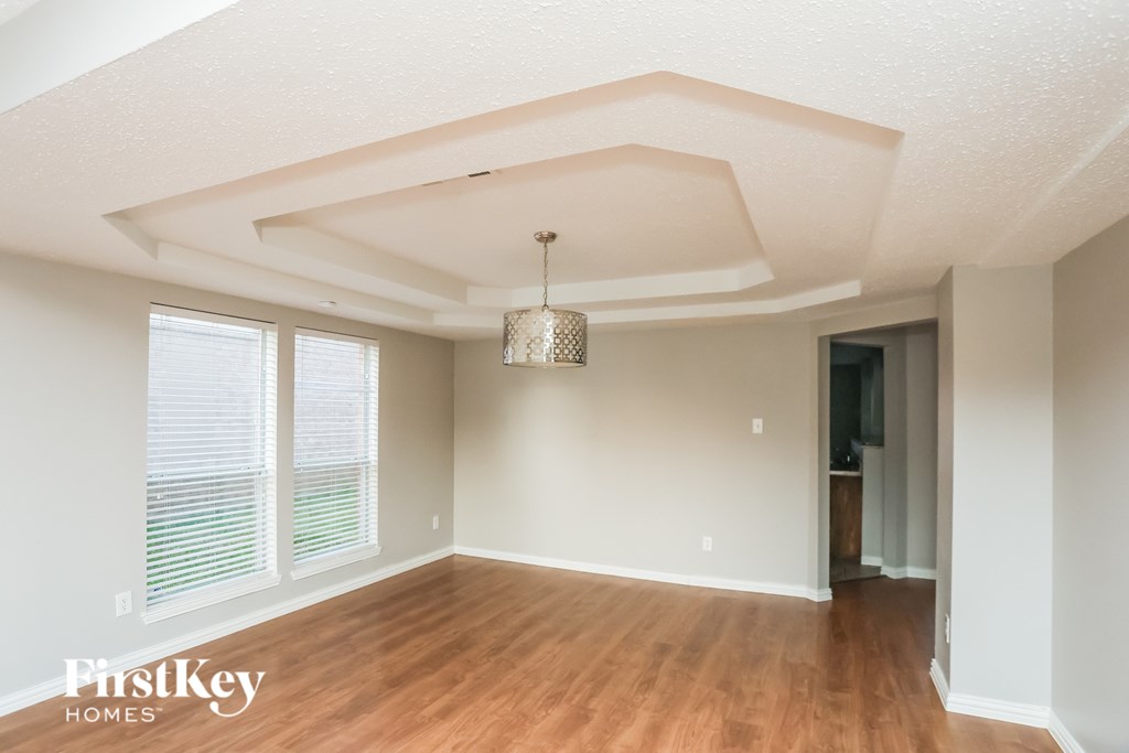 A room with wooden floors and a chandelier hanging from the ceiling.