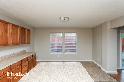 A kitchen with wooden cabinets and a window with blinds.