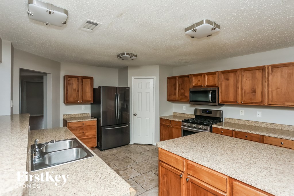 A kitchen with wooden cabinets and a black refrigerator.