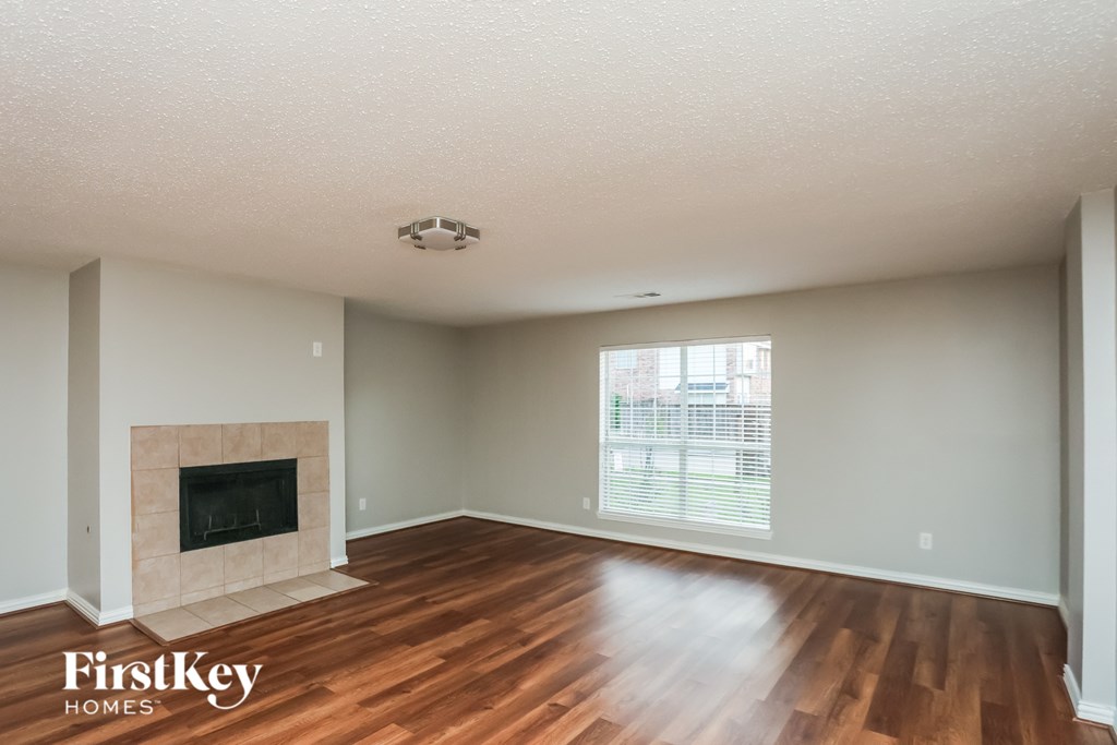 A spacious living room with a fireplace and wooden floors.
