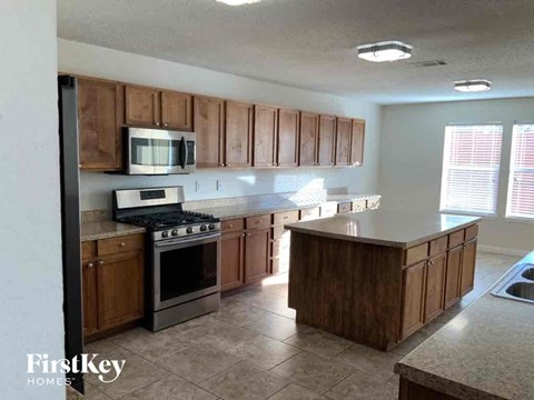 A kitchen with wooden cabinets and a stove top oven.
