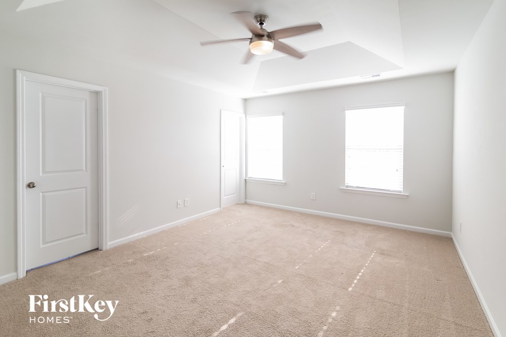 a bedroom with white walls and a ceiling fan and a white door