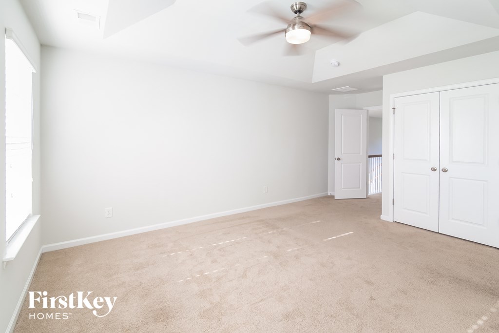 a empty living room with white walls and a ceiling fan