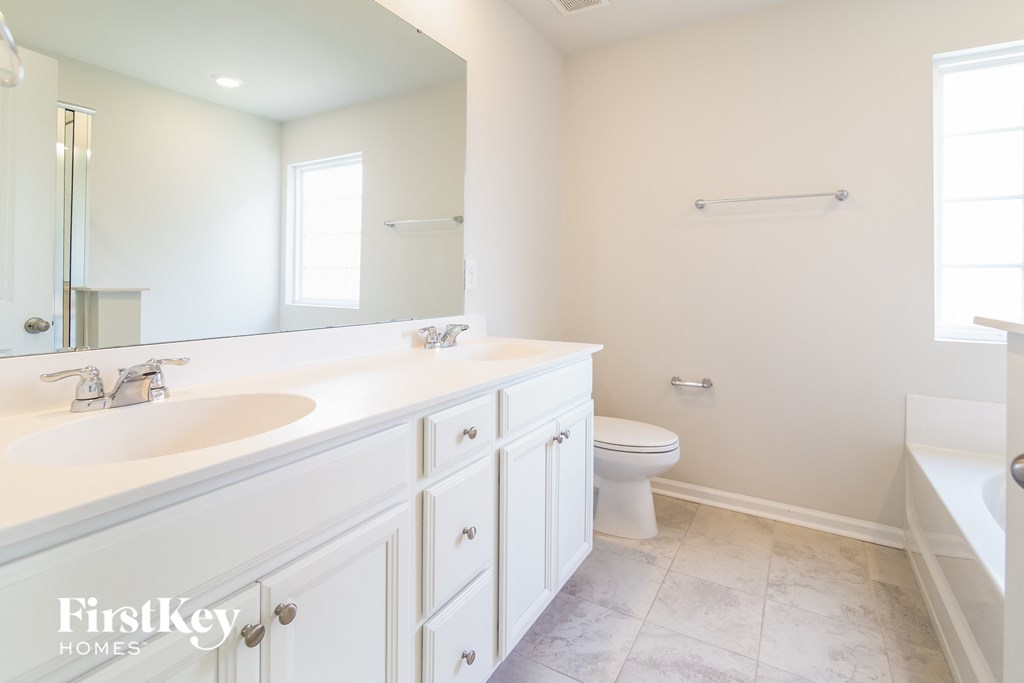 a white bathroom with a large mirror and a sink and a toilet