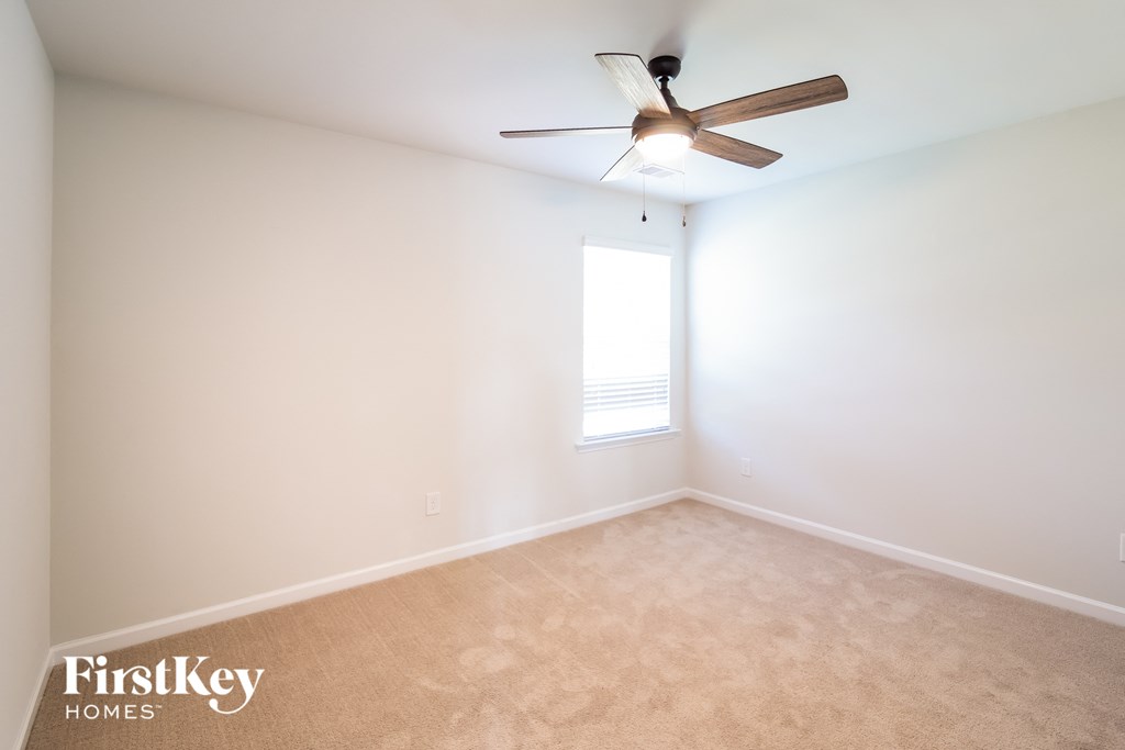 an empty room with a ceiling fan and a window