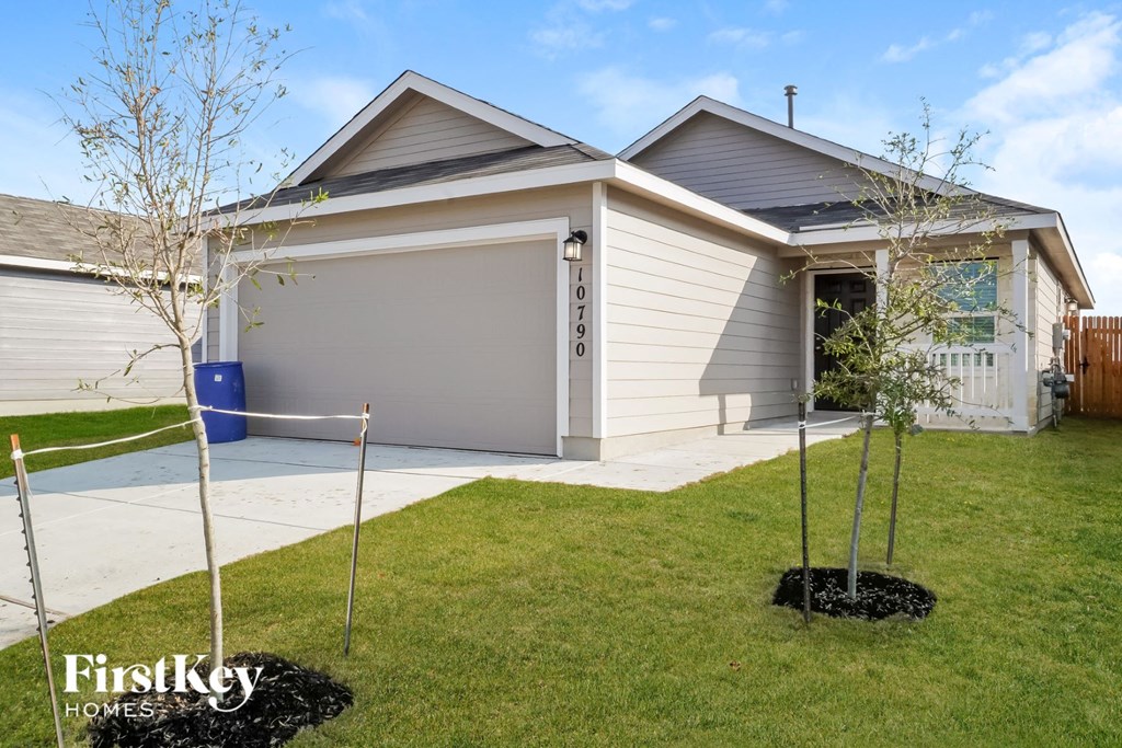 the front yard of a house with newly planted trees