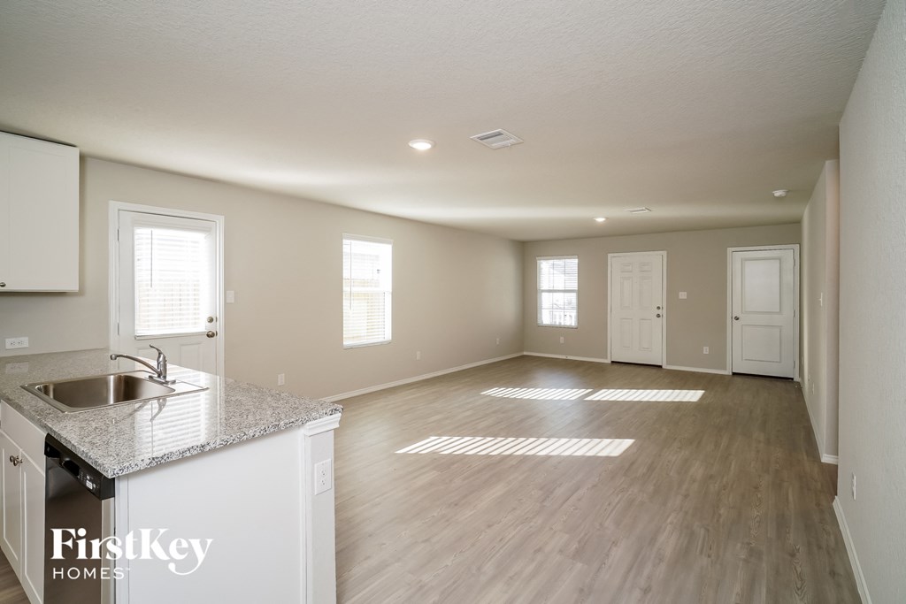 a kitchen and living room with white cabinets and hardwood floors