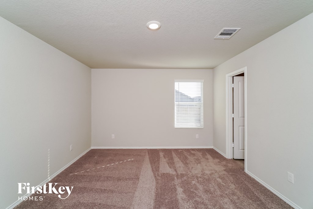 a spacious living room with carpet and a door to the bathroom