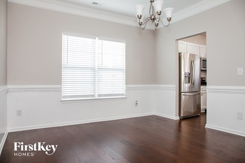 a kitchen with white walls and wood floors and a stainless steel refrigerator