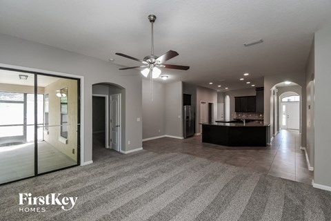 A spacious living room with a ceiling fan and a striped carpet.