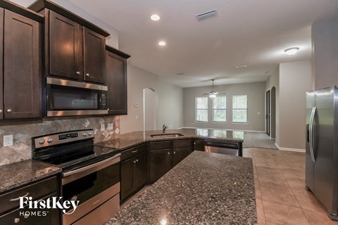 A kitchen with dark brown cabinets and granite countertops.