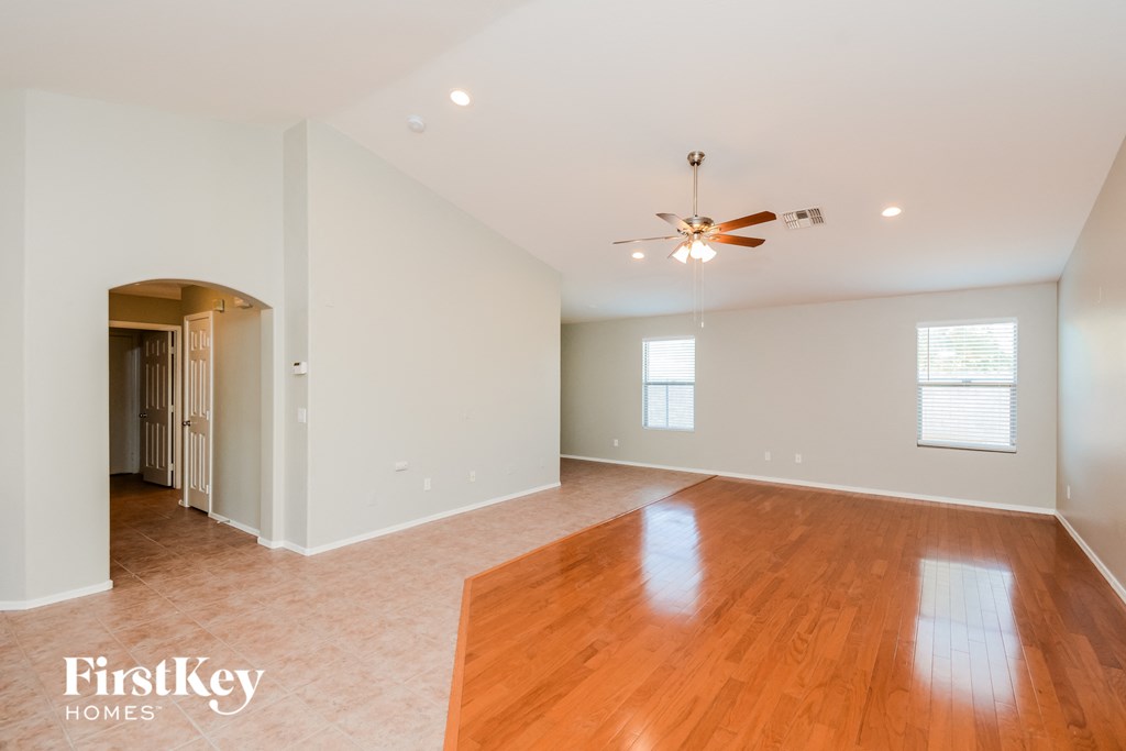 A spacious room with wooden floors and a ceiling fan.