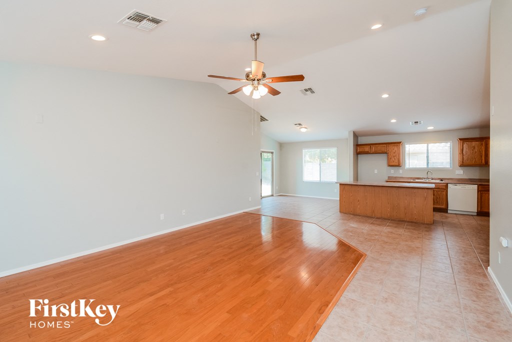 A spacious room with a wooden floor and a ceiling fan.