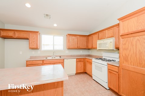 A kitchen with wooden cabinets and a white stove top oven.