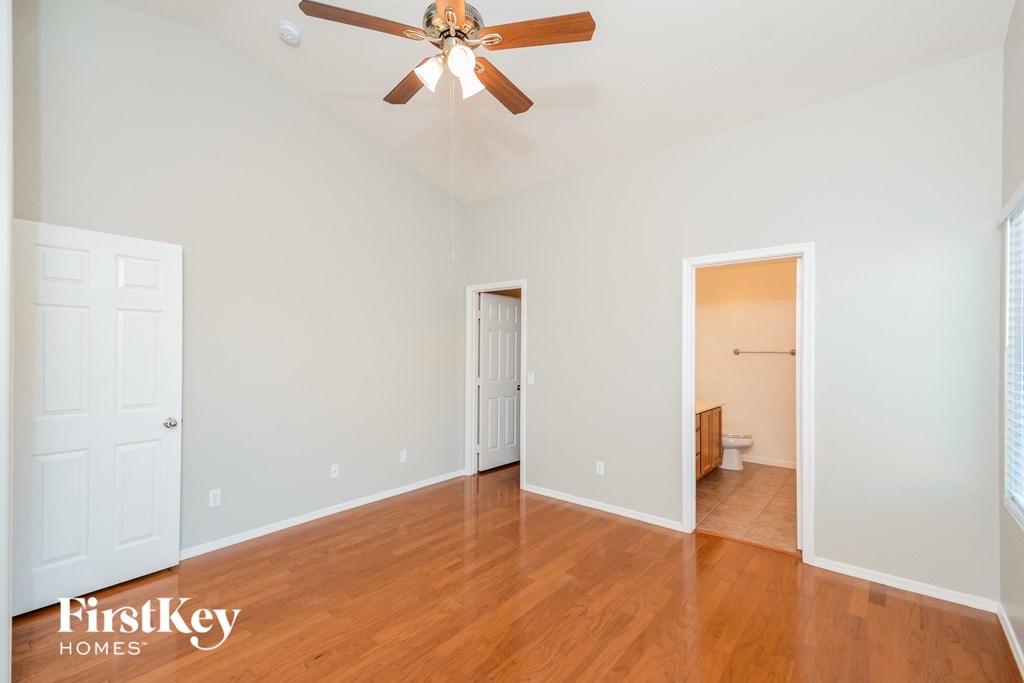 A room with a ceiling fan and wooden floors.