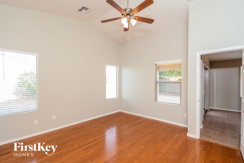 A room with a ceiling fan and wooden floors.