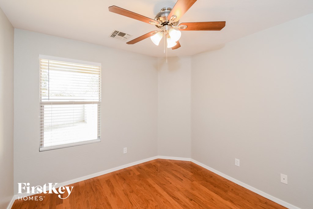 A room with a ceiling fan and a window with blinds.