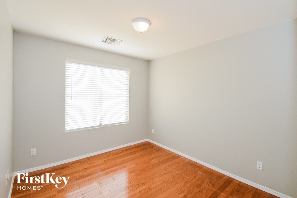 A room with wooden floors and a window with blinds.