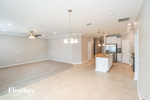 A spacious living room with a kitchen in the background.