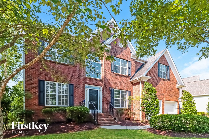 a red brick house with black shutters and a tree