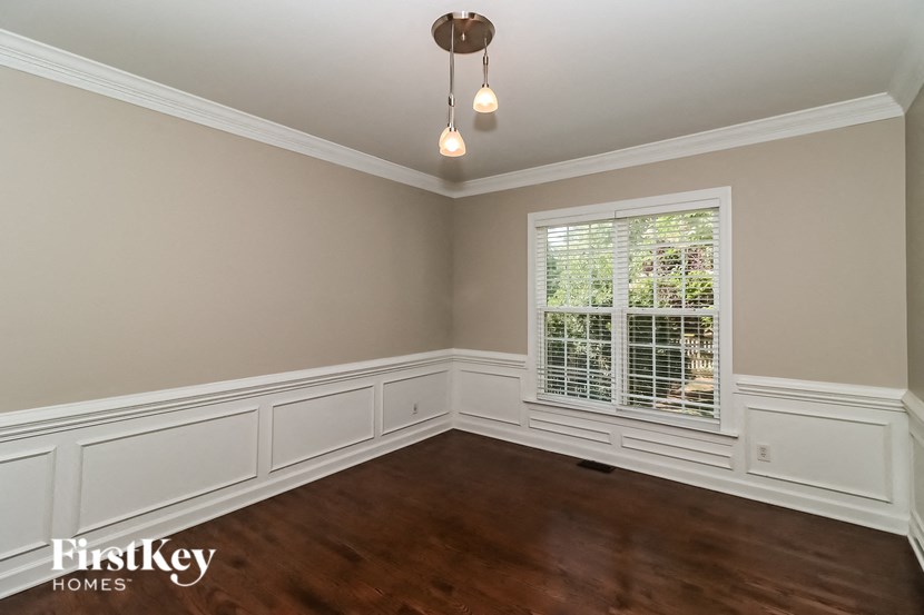 a dining room with white wainscoting and a window