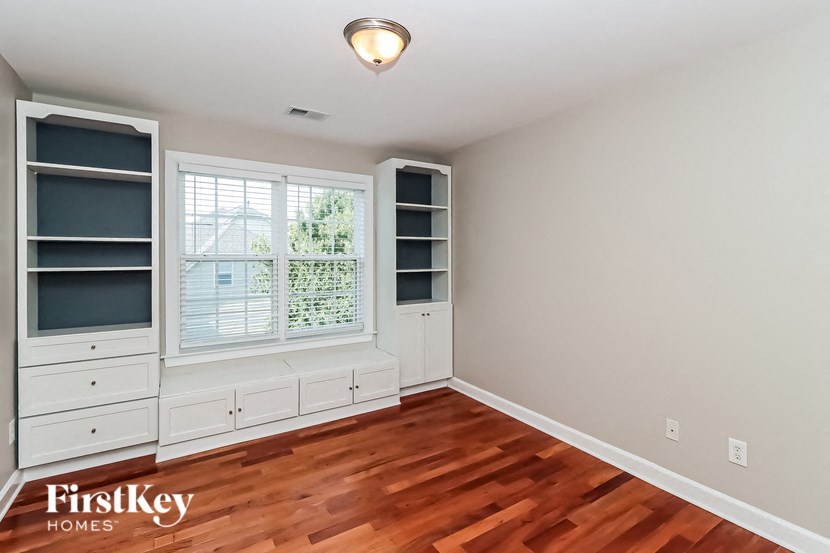 a bedroom with white cabinets and a window and wood floors