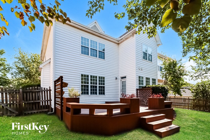 a backyard patio with a wooden deck and a white house